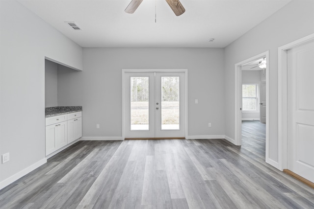 interior space with a wealth of natural light, light hardwood / wood-style floors, and french doors