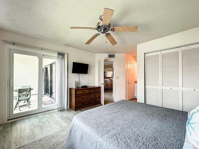 bedroom with ceiling fan, access to exterior, a textured ceiling, light hardwood / wood-style floors, and a closet