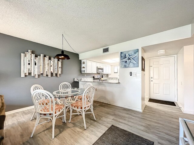 dining room with a textured ceiling and light hardwood / wood-style floors