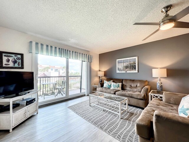 living room with ceiling fan, wood-type flooring, and a textured ceiling