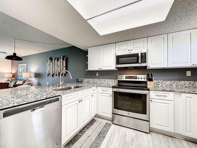 kitchen featuring white cabinets, sink, light wood-type flooring, a textured ceiling, and appliances with stainless steel finishes