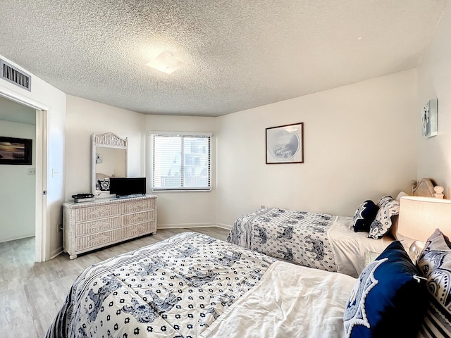 bedroom with light hardwood / wood-style flooring and a textured ceiling