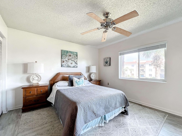 bedroom featuring ceiling fan, light hardwood / wood-style floors, and a textured ceiling