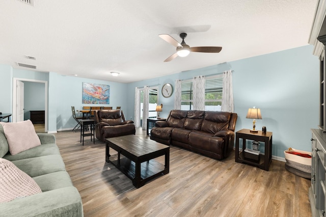 living room featuring ceiling fan, light hardwood / wood-style floors, and a textured ceiling