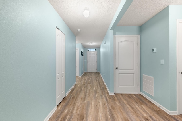 corridor with hardwood / wood-style flooring and a textured ceiling