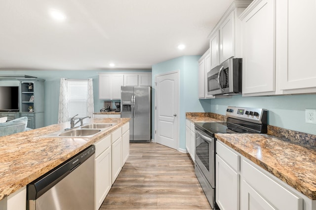 kitchen with white cabinetry, sink, light stone countertops, and appliances with stainless steel finishes