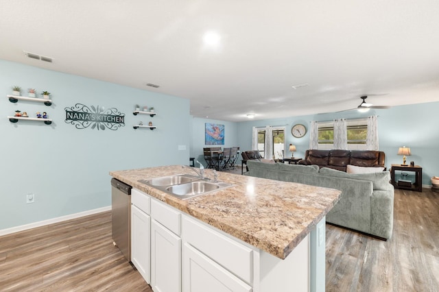 kitchen with stainless steel dishwasher, ceiling fan, sink, white cabinets, and an island with sink