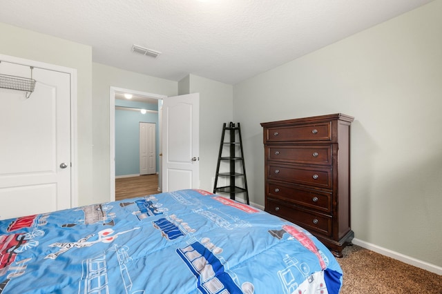 carpeted bedroom featuring a textured ceiling and a closet