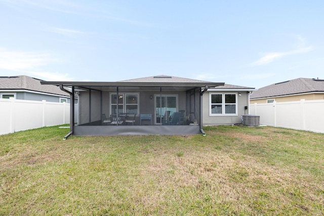 rear view of house with a sunroom, a lawn, and central AC