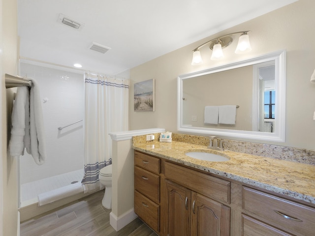 6240 A1A S Unit 103, Saint Augustine, FL 32080 - bathroom featuring visible vents, a tile shower, toilet, vanity, and wood finished floors