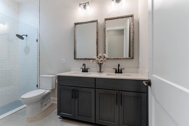 bathroom featuring tile patterned flooring, vanity, tiled shower, and toilet