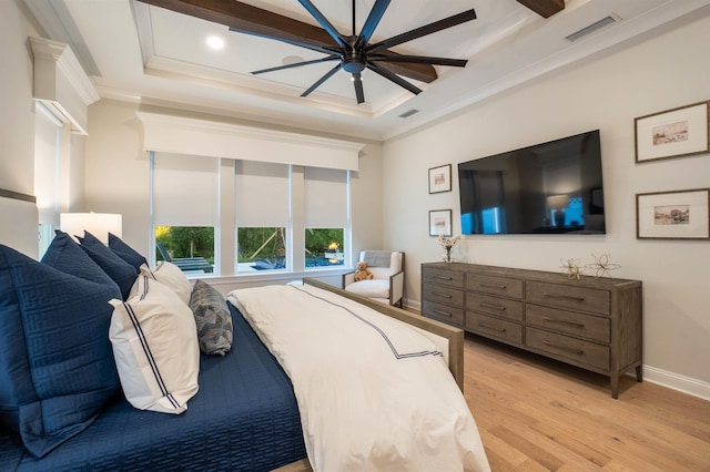 bedroom with crown molding, light hardwood / wood-style flooring, ceiling fan, and a tray ceiling