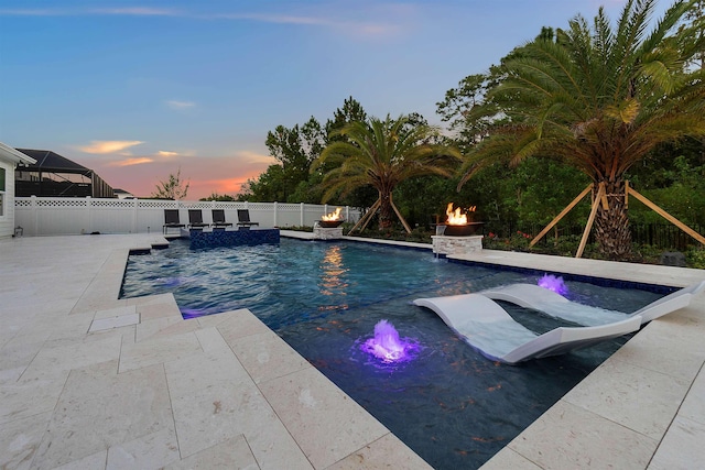 pool at dusk with pool water feature, an outdoor fire pit, and a patio