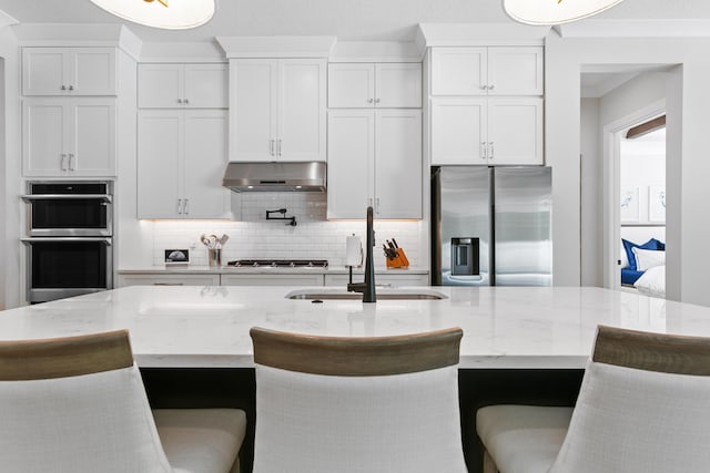 kitchen featuring white cabinetry, appliances with stainless steel finishes, a breakfast bar, and a center island with sink