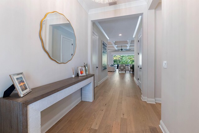 hallway featuring beamed ceiling, ornamental molding, coffered ceiling, and light wood-type flooring