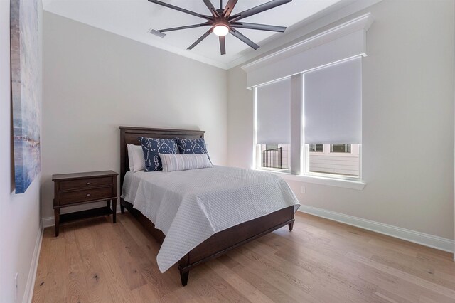 bedroom with crown molding, light hardwood / wood-style flooring, and ceiling fan