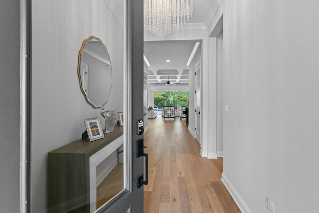 hall with coffered ceiling, an inviting chandelier, beam ceiling, and light hardwood / wood-style flooring