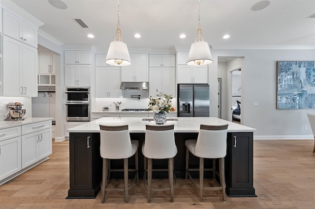 kitchen with white cabinets, hanging light fixtures, a spacious island, and appliances with stainless steel finishes