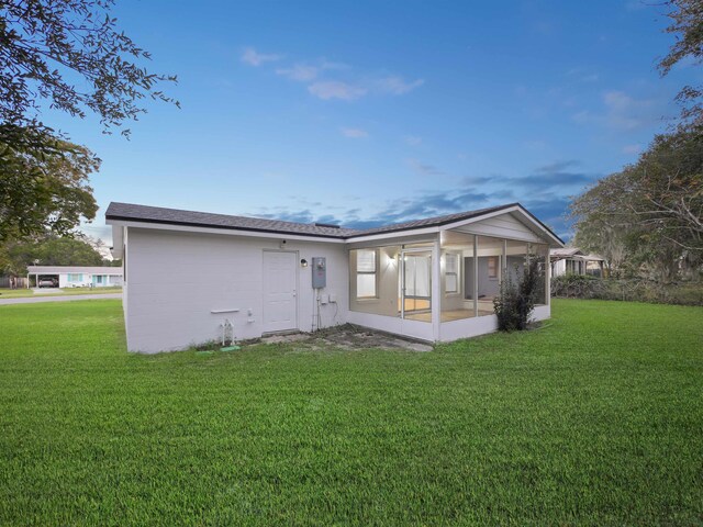 rear view of house featuring a sunroom and a yard