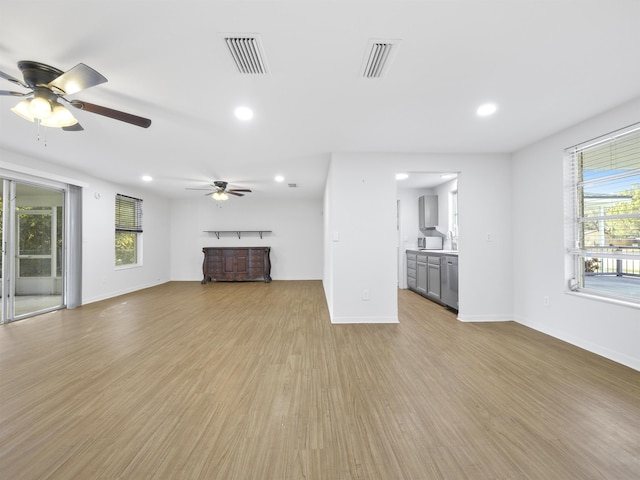 unfurnished living room featuring plenty of natural light, light hardwood / wood-style floors, and ceiling fan