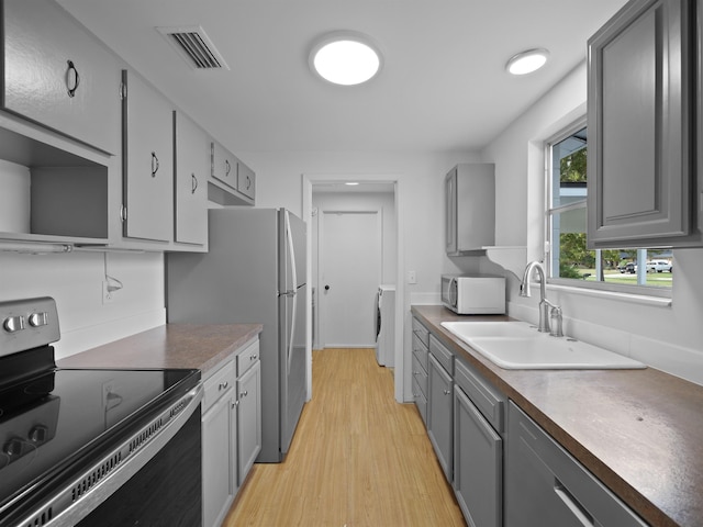 kitchen with sink, black electric range, light hardwood / wood-style flooring, washer / clothes dryer, and gray cabinets