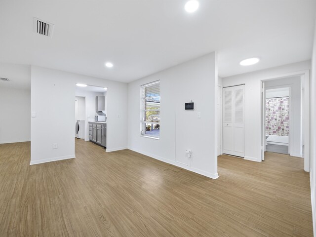 unfurnished living room with washer / dryer and light wood-type flooring