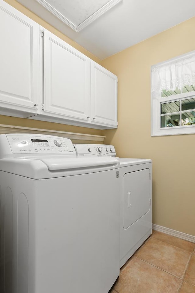 laundry area with light tile patterned floors, baseboards, cabinet space, and washing machine and clothes dryer