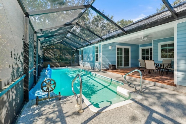 view of swimming pool with glass enclosure, a patio, a ceiling fan, and a fenced in pool