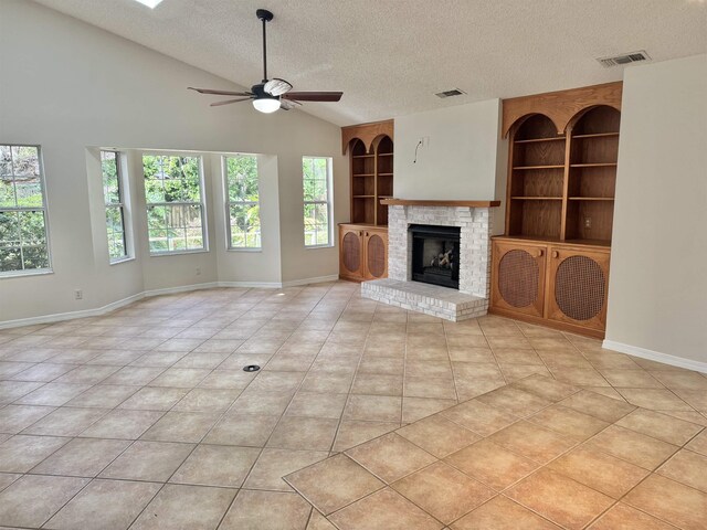 unfurnished room with lofted ceiling with skylight, light tile patterned floors, a textured ceiling, and a ceiling fan