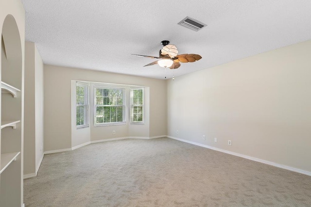 carpeted spare room with baseboards, visible vents, a textured ceiling, and a ceiling fan