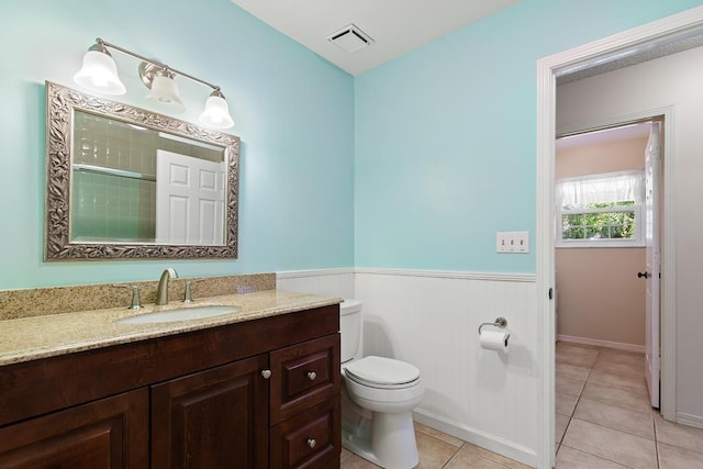 bathroom with tile patterned flooring, visible vents, toilet, wainscoting, and vanity