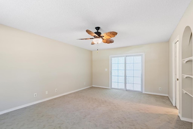 carpeted empty room with a ceiling fan, baseboards, and a textured ceiling