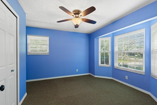 unfurnished bedroom featuring multiple windows, carpet, baseboards, and a textured ceiling