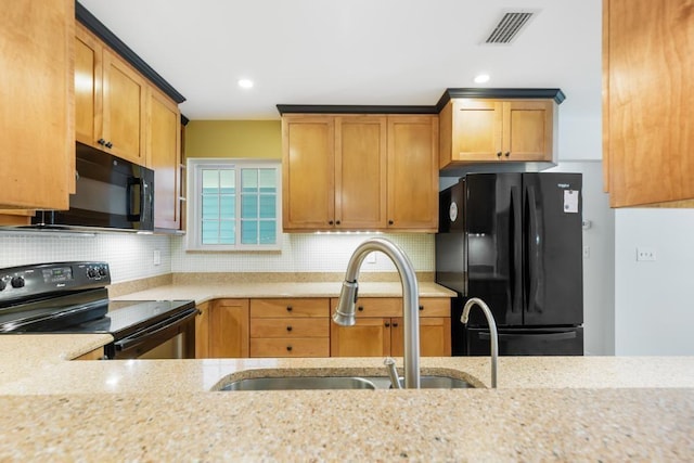 kitchen with visible vents, black appliances, a sink, tasteful backsplash, and light stone countertops