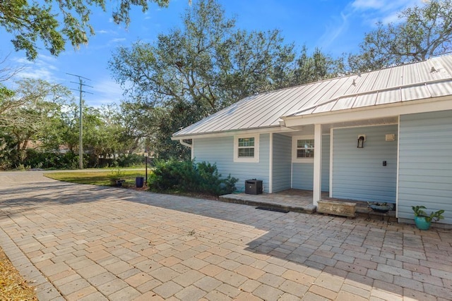 exterior space with central AC unit, metal roof, and a standing seam roof