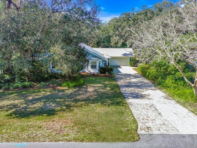 view of front facade with metal roof, decorative driveway, and a front lawn