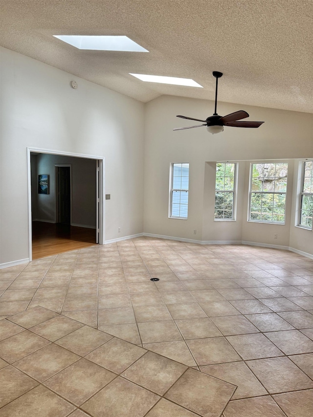 empty room with light tile patterned flooring, baseboards, a textured ceiling, and a ceiling fan