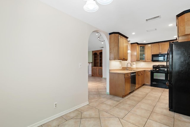 kitchen with light tile patterned floors, visible vents, arched walkways, black appliances, and light countertops