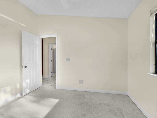 spare room featuring light carpet and a textured ceiling