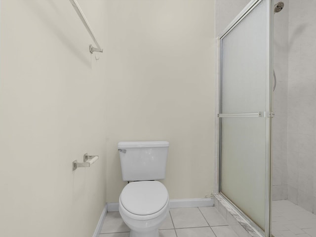 bathroom featuring tile patterned flooring, toilet, and a shower with door