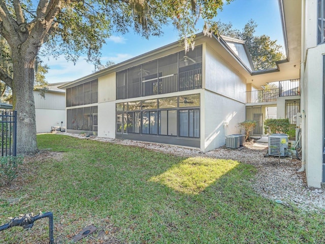 rear view of house featuring a sunroom, cooling unit, and a yard