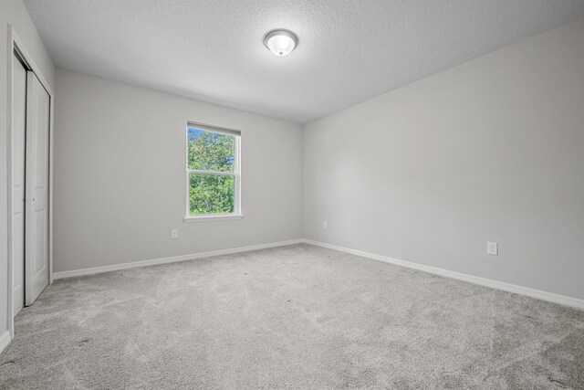 249 La Mancha Dr, Saint Augustine, FL 32086 - unfurnished bedroom with carpet floors, baseboards, a closet, and a textured ceiling