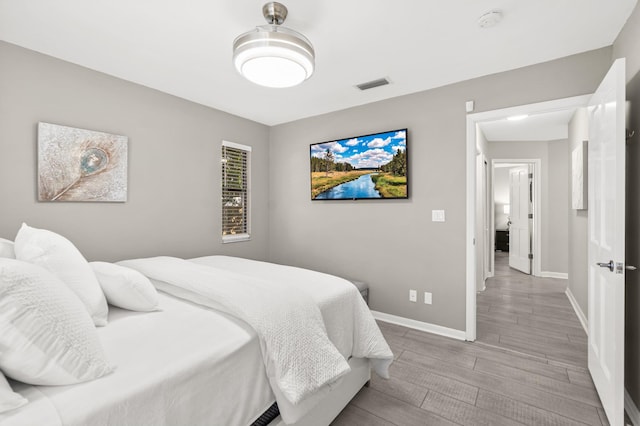 bedroom featuring wood finished floors, visible vents, and baseboards