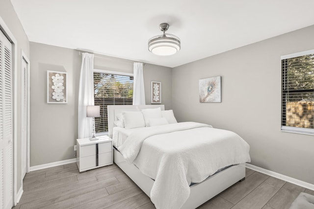 bedroom with light wood finished floors, baseboards, and a closet