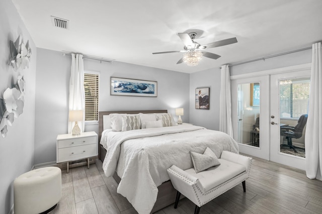 bedroom with a ceiling fan, access to exterior, french doors, and wood finished floors