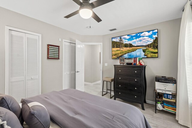 bedroom featuring multiple closets, visible vents, ceiling fan, and baseboards