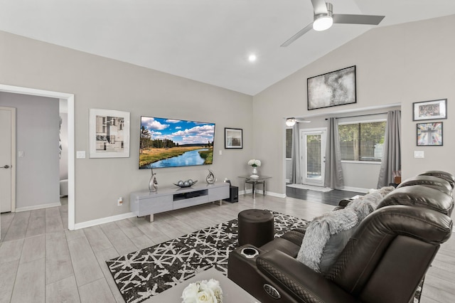 living area featuring a ceiling fan, baseboards, high vaulted ceiling, and light wood finished floors