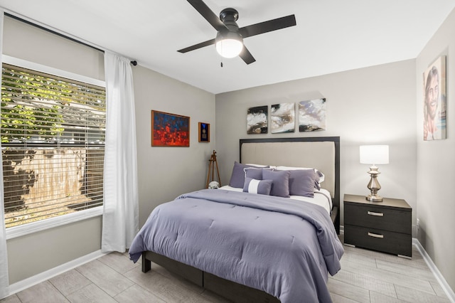 bedroom with a ceiling fan, multiple windows, and baseboards