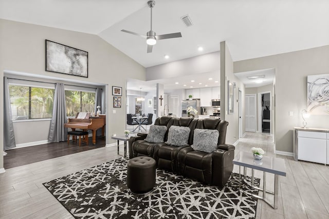 living area with light wood finished floors, a ceiling fan, visible vents, and baseboards