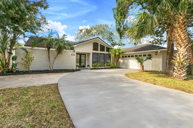 view of front of property with driveway, a garage, french doors, and stucco siding